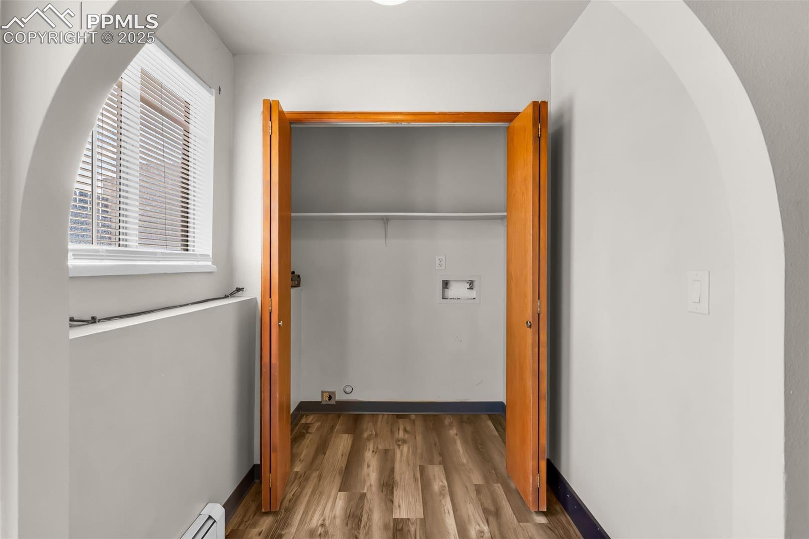 Laundry closet featuring a baseboard heating unit