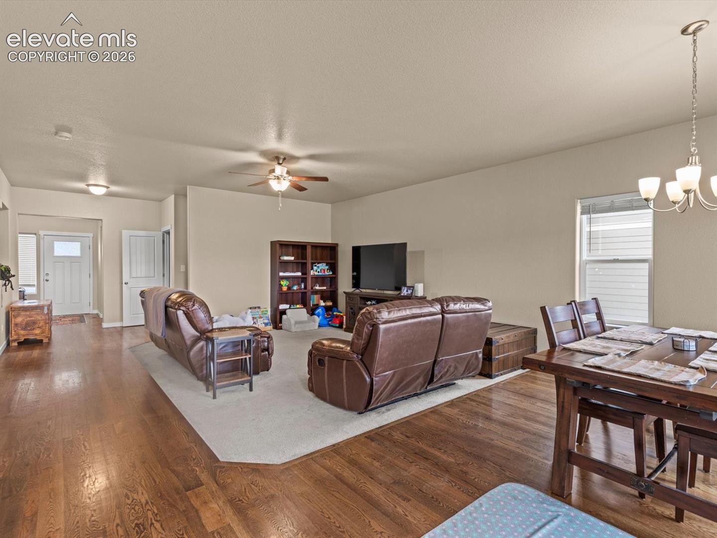Open-concept living area featuring rich wood-finish flooring, recessed lighting, and a ceiling fan