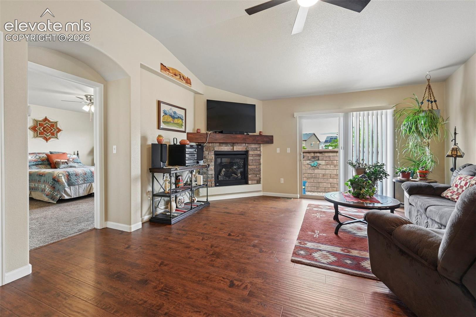 Living room offers a cozy gas fireplace with brick surround and ceiling fan