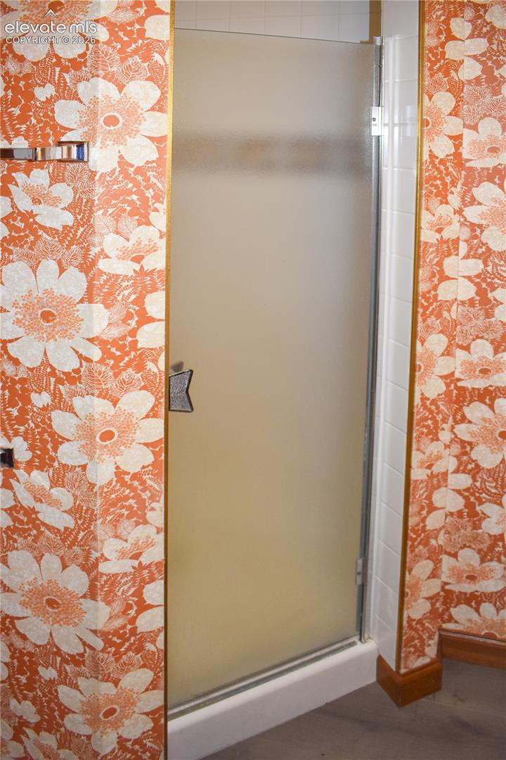 Enclosed shower with frosted glass door, white tile surround, and gold-finish trim