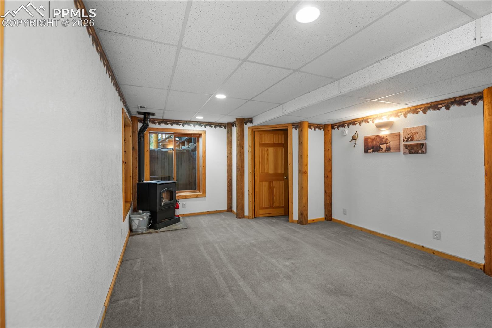 Unfurnished living room featuring a wood stove, a drop ceiling, carpet, and recessed lighting