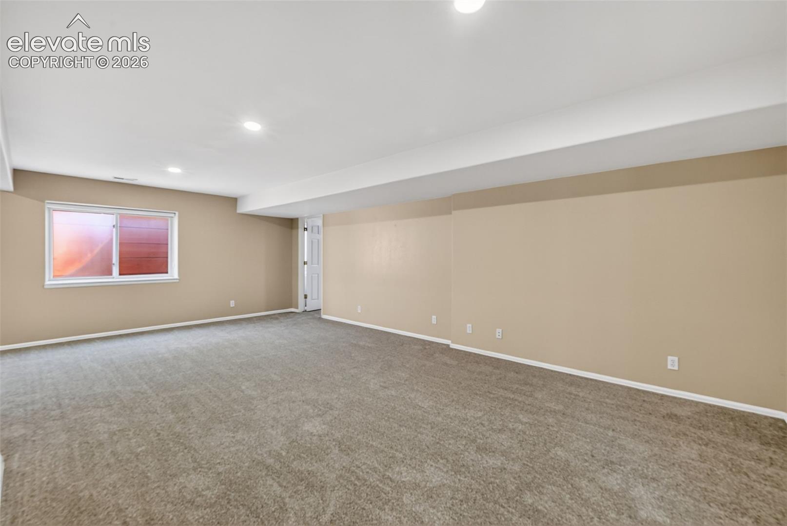 Open-concept interior featuring neutral wall tones, wall-to-wall carpeting, recessed ceiling lighting, and a single-pane window