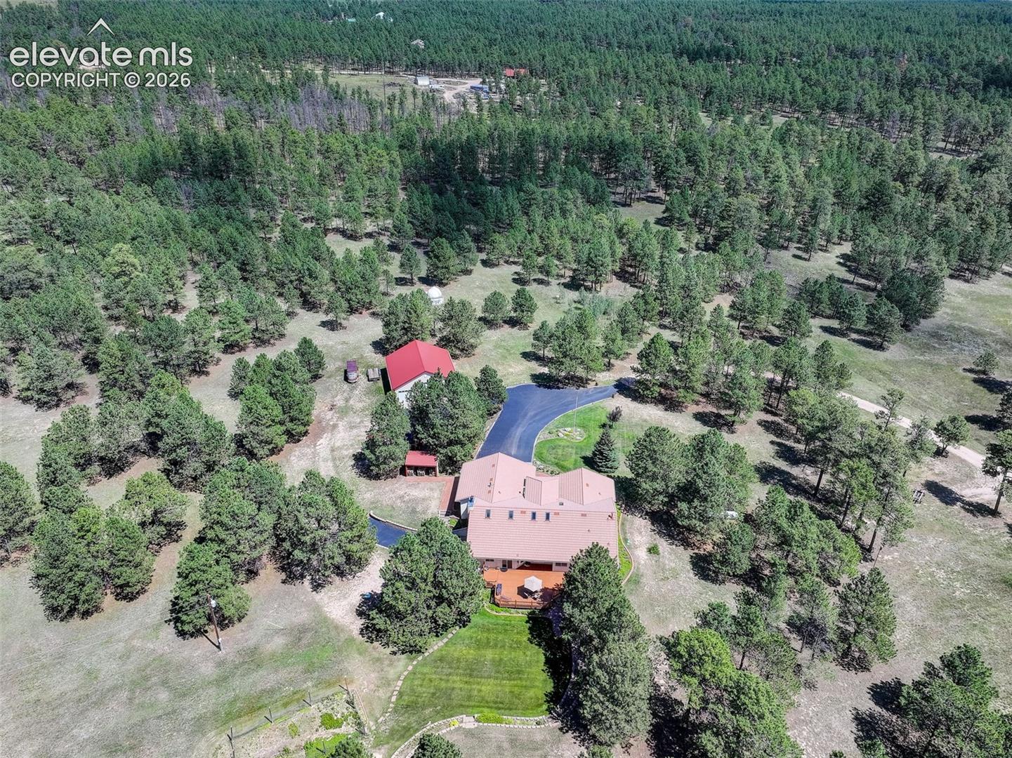 Aerial view of property with landscaped back yard, fenced garden, RV workshop, heated driveway and mature trees. 