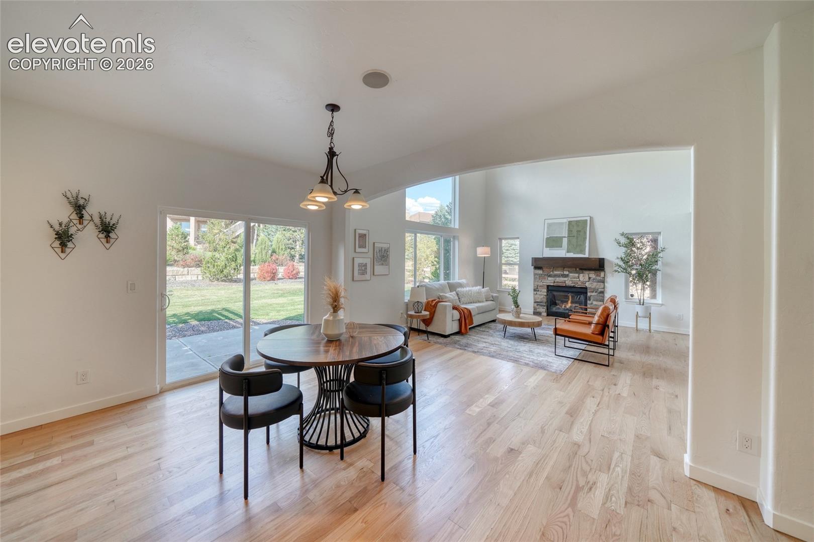 Hardwood flooring throughout, recessed lighting, and a stone fireplace with a wood mantle