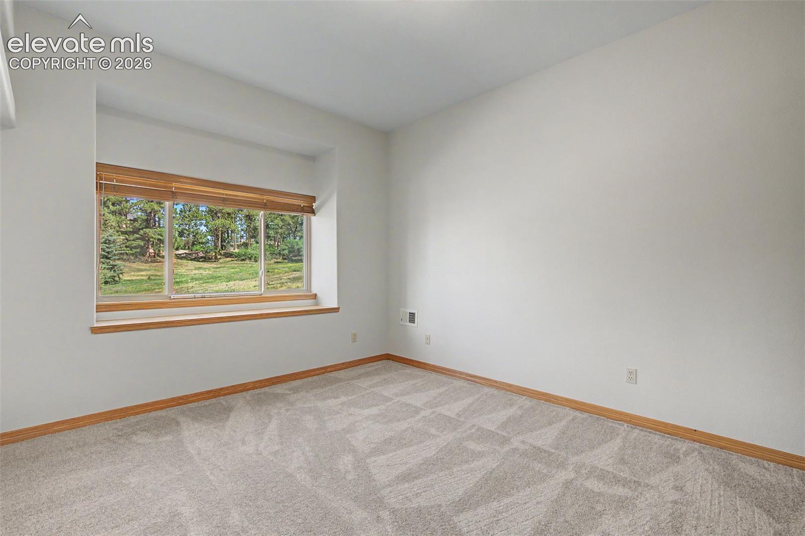 Recessed window with wood-finish trim, beige blinds, and a natural landscape beyond