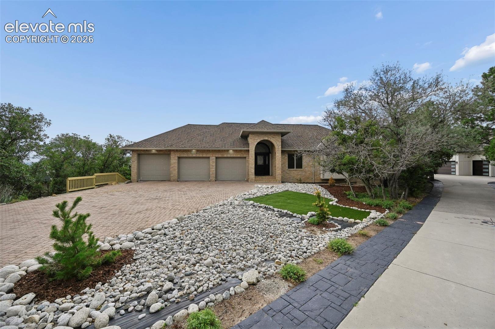 Stunning contemporary residence showcasing a three-car garage with arched architectural detailing, paired with an expansive paver driveway featuring geometric patterns