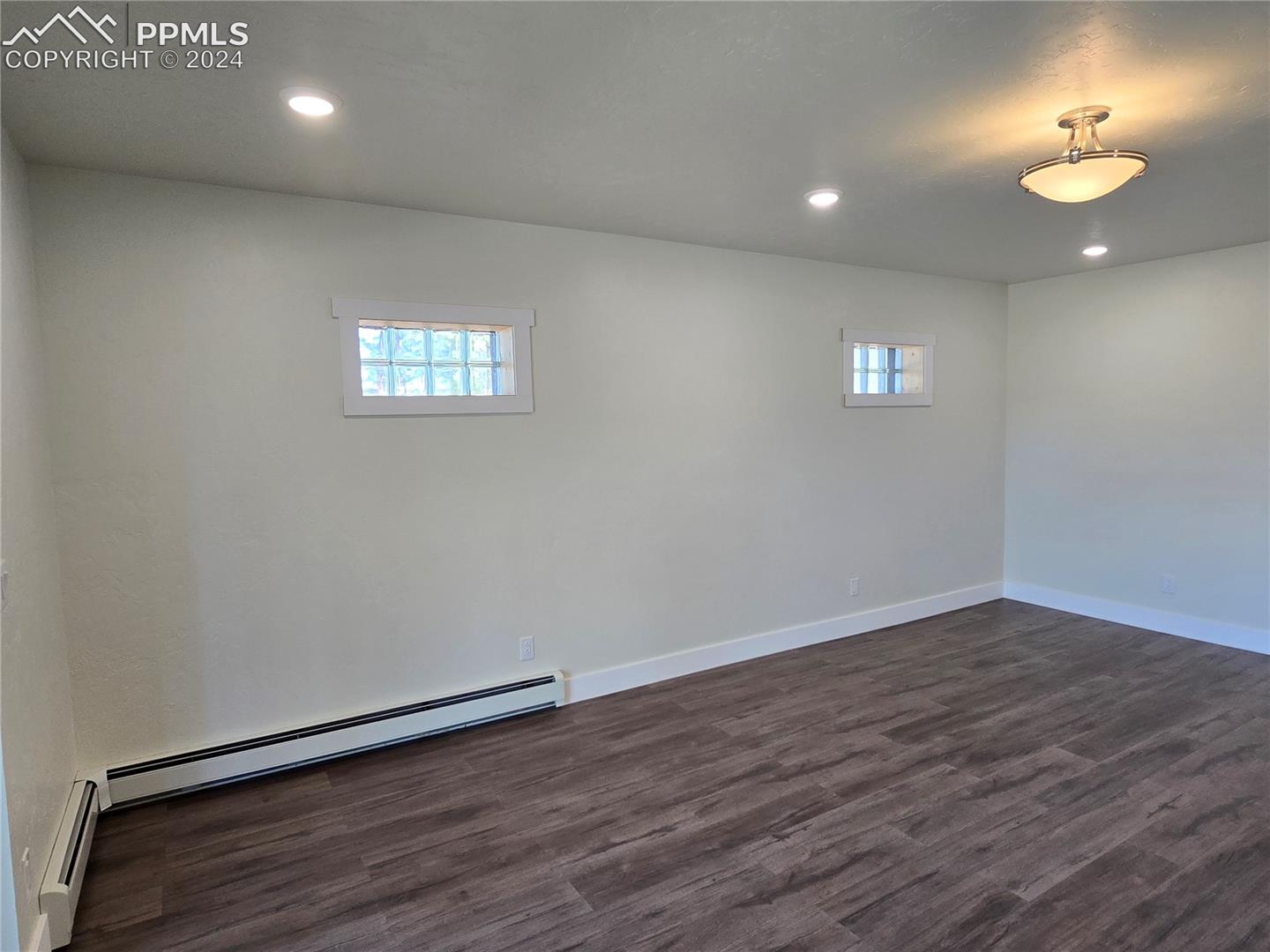 Basement featuring a baseboard radiator and dark hardwood / wood-style floors