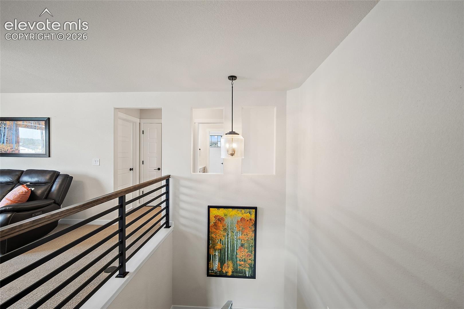 Contemporary wood-finish handrail with black metal balusters, overhead pendant lighting.Great opportunity for gallery wall!