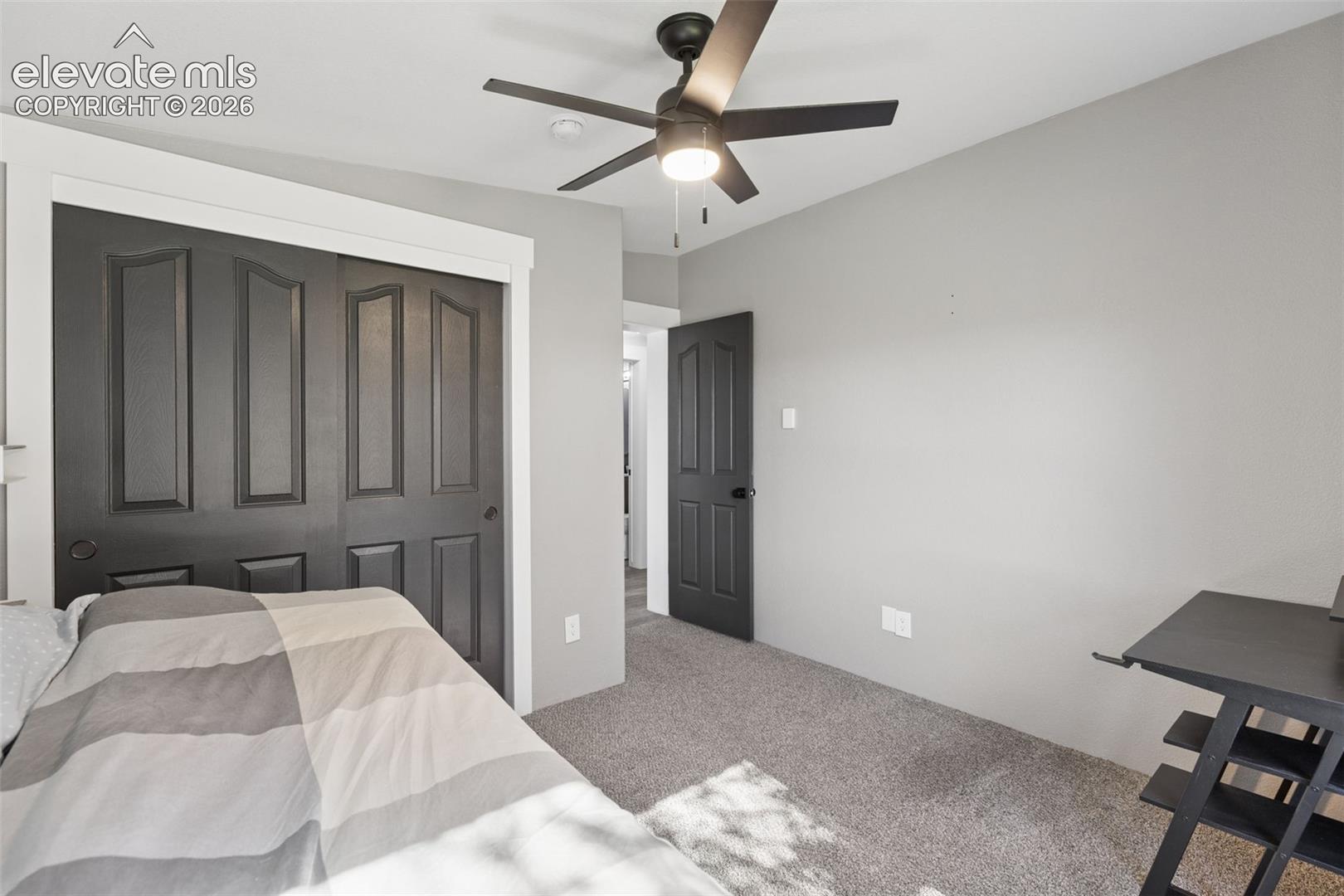 Neutral-toned room featuring a ceiling fan with integrated light, dark-toned interior doors, and carpeted flooring