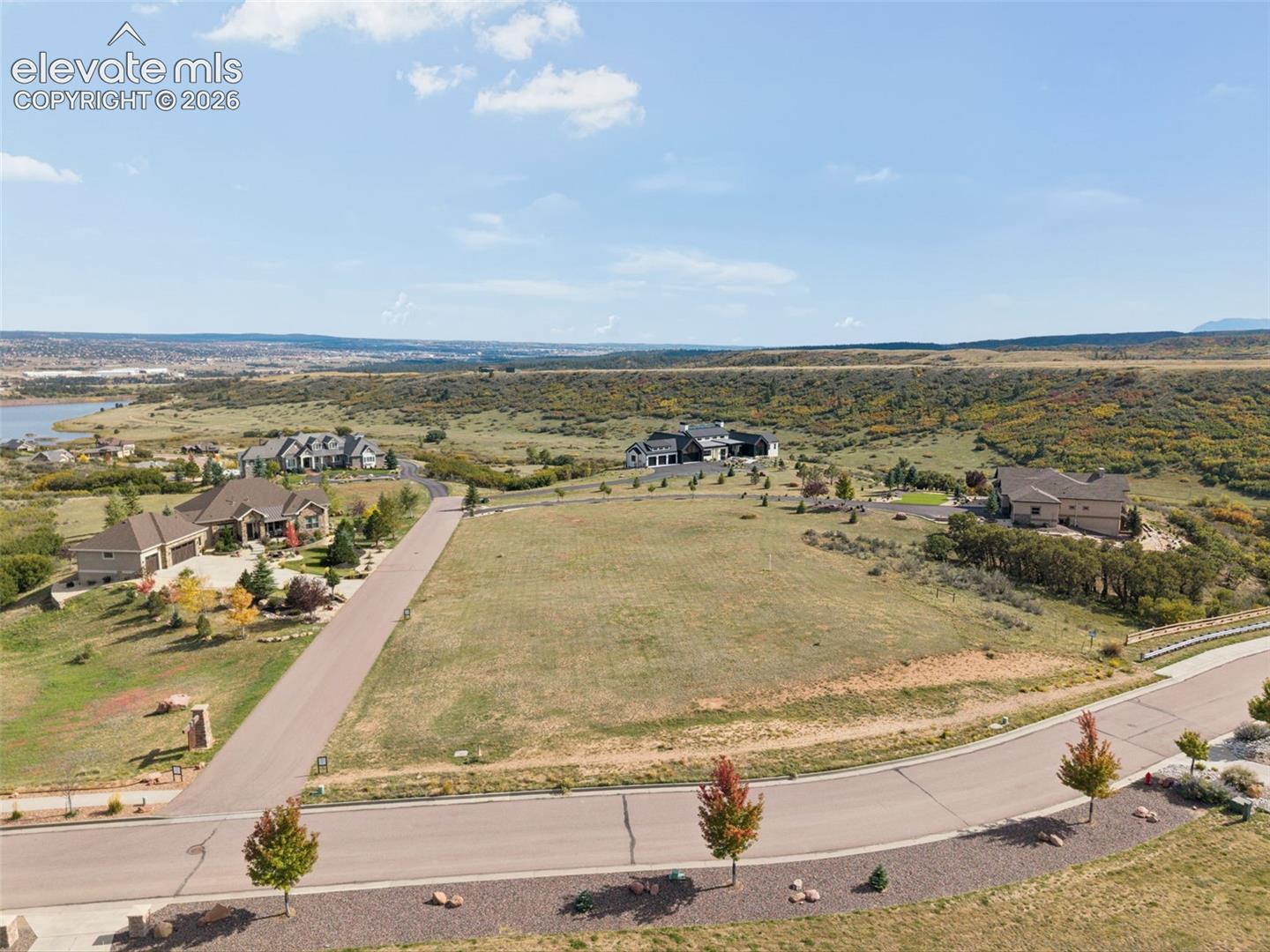 Expansive vacant lot featuring frontage on a paved cul-de-sac, native grass landscaping, and regional mountain and water scenery