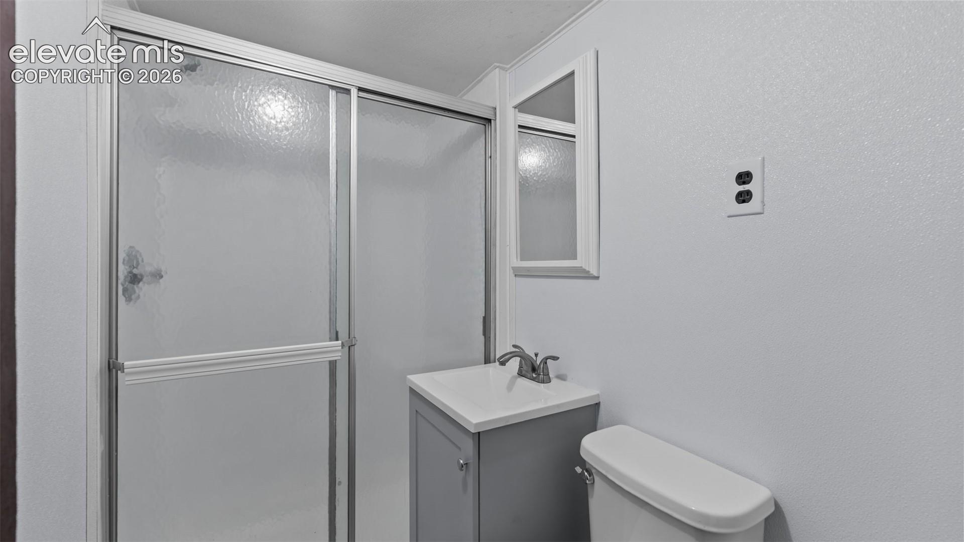Shower with sliding textured glass doors, single vanity with integrated sink, chrome faucet, wall-mounted mirror