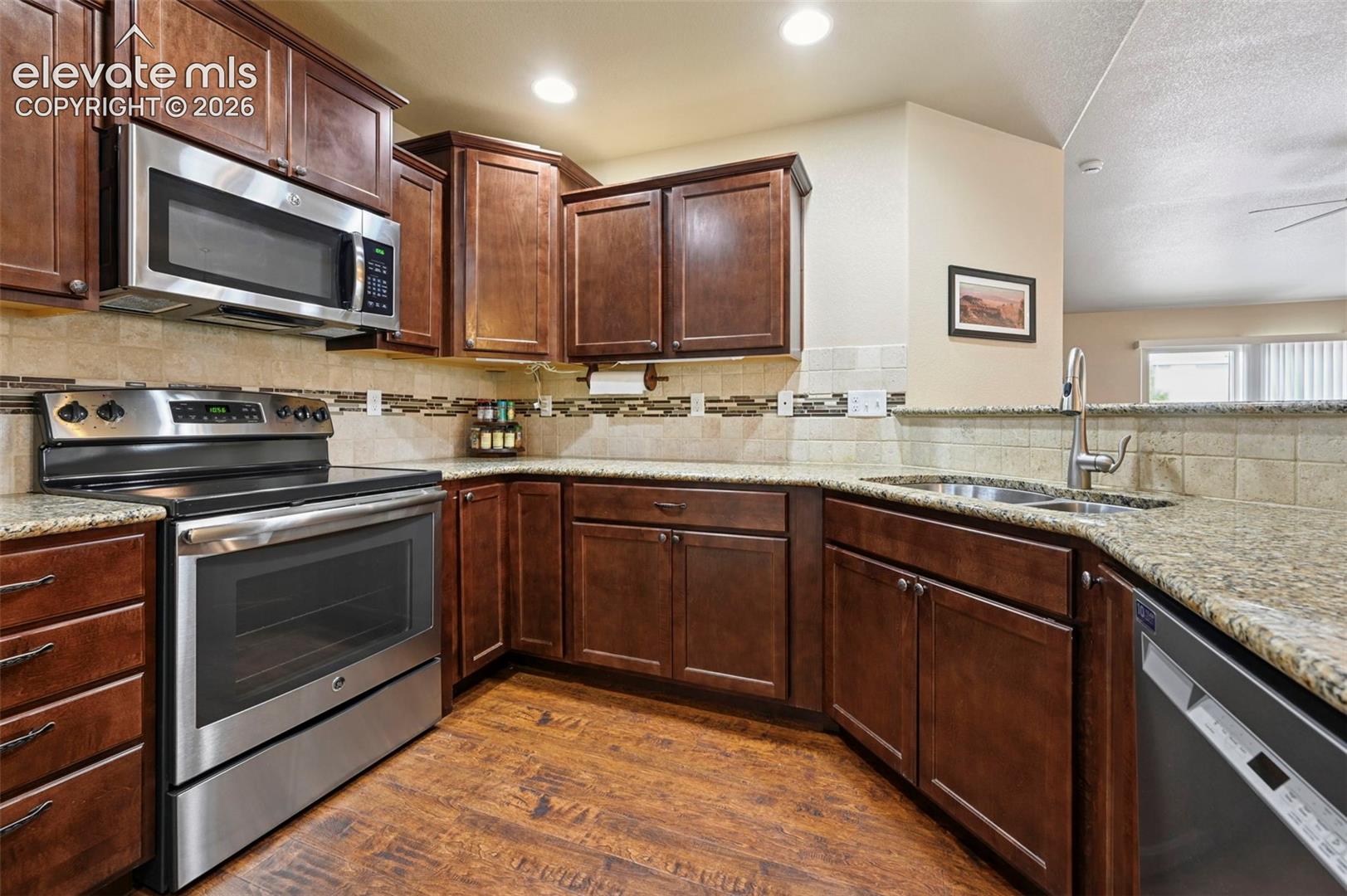 Kitchen featuring dark wood cabinetry, under cabinet lighting and stainless steel appliances