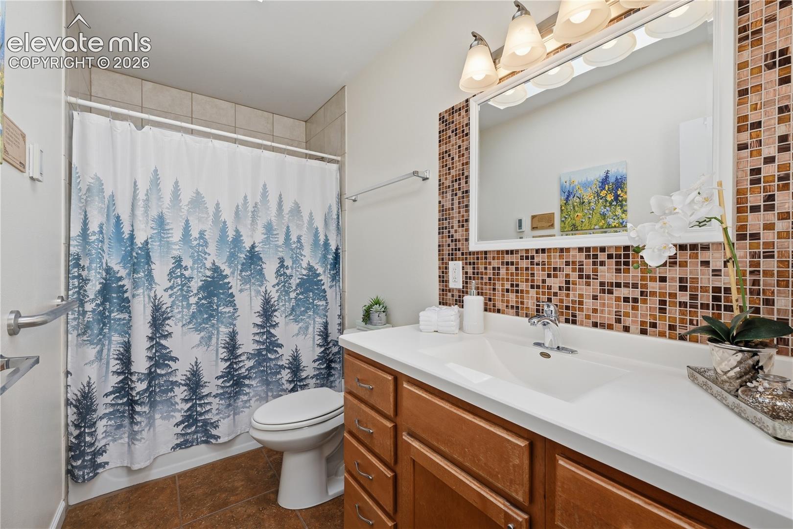 Full bathroom offers a functional layout with generous vanity space and attractive tile accents.