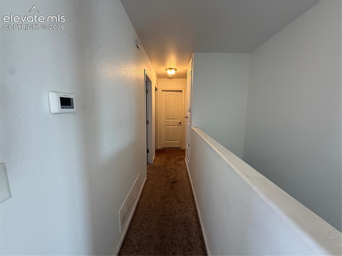 Hallway featuring carpeting, arched-panel interior doors, and a flush-mount light fixture