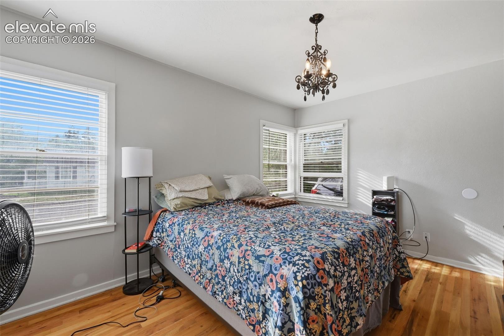 Hardwood-finish flooring, two window units, and an ornate chandelier