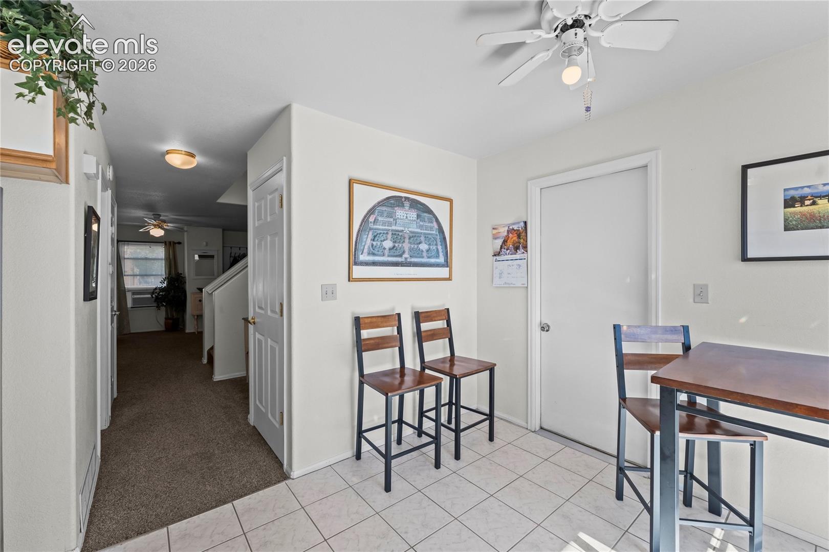 White tile flooring, overhead ceiling fan, white paneled doors, and neutral wall paint