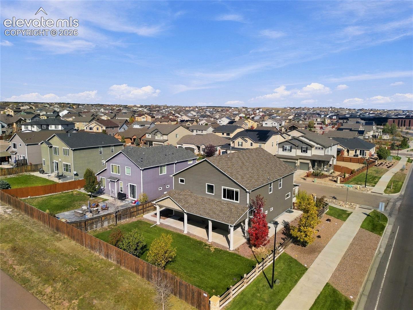 Two-story residence featuring a covered rear patio, fully fenced backyard with established landscaping, and an attached multi-car garage