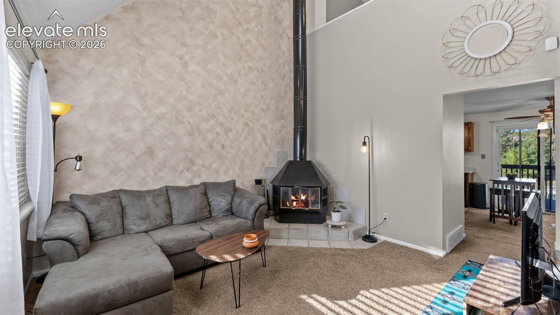 Vaulted ceilings, a freestanding wood-burning fireplace with a tile hearth, and textured accent wall