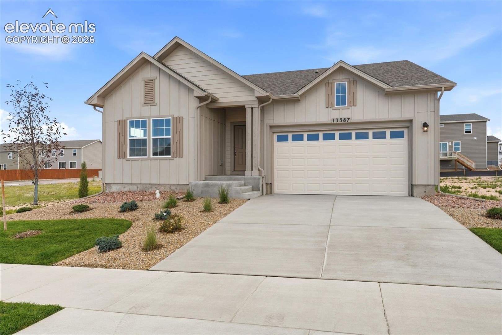 Single-story exterior featuring vertical siding, a paneled garage door, decorative shutters, and a concrete driveway