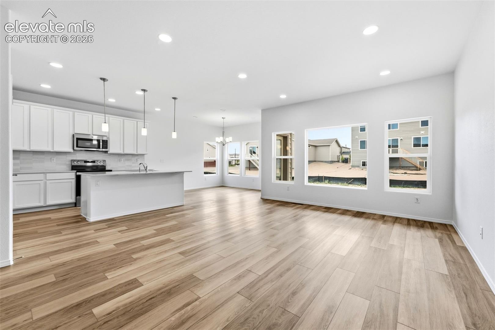 Kitchen featuring white cabinetry, an island with countertop seating, recessed lighting, and wood-finish flooring