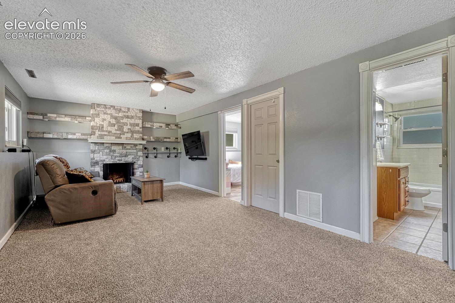 The Lower Level Living Room features brand new carpet, a lighted ceiling fan, and wood burning fireplace with stone surround to cozy up on winter nights.