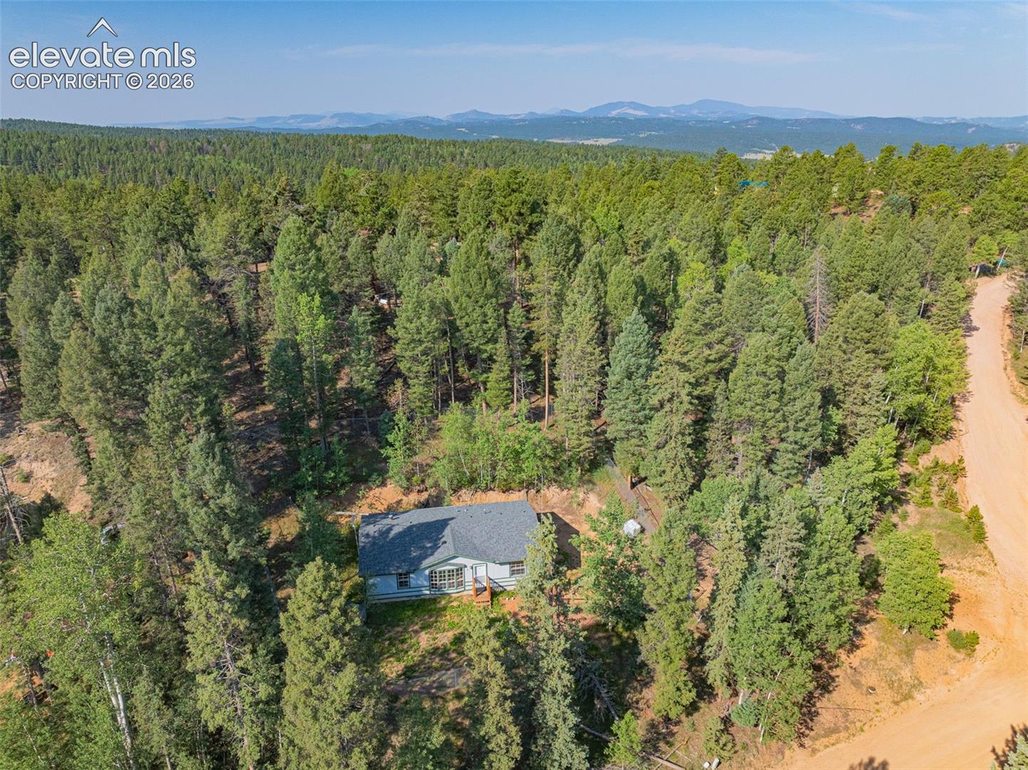 Wooded acreage with a single-story residence and a gravel drive