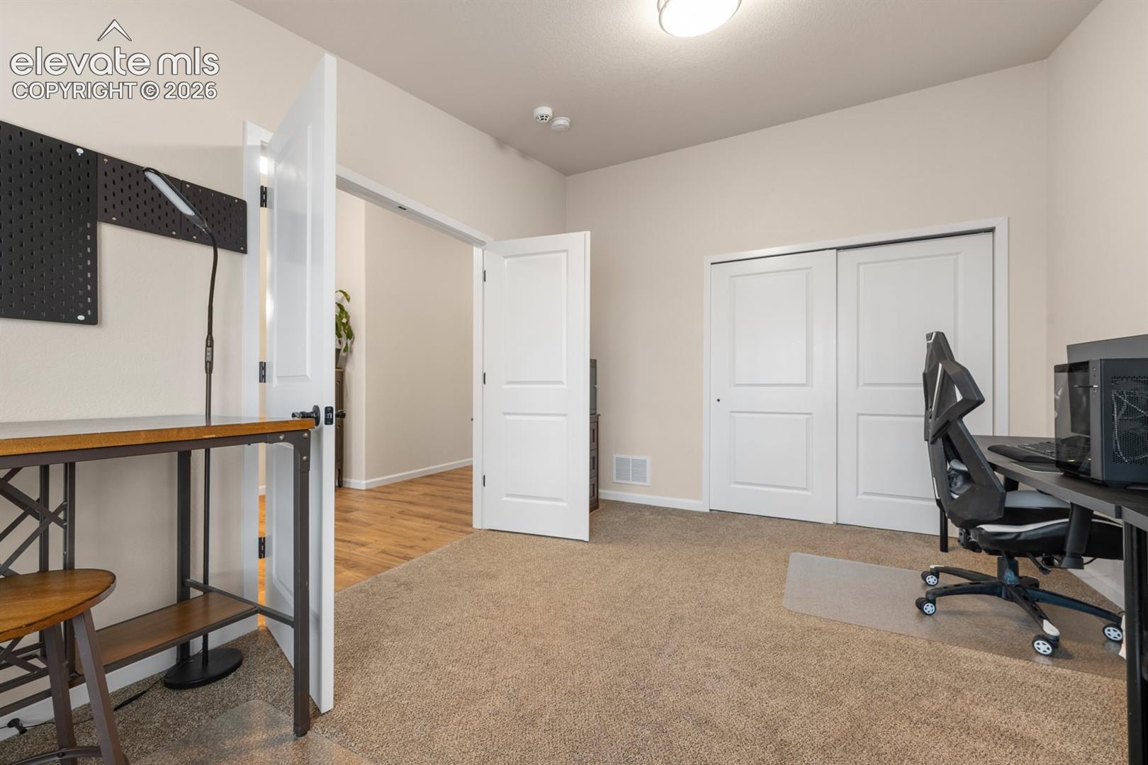 Room featuring neutral-toned carpeting, two-panel interior doors, and a double-door reach-in closet