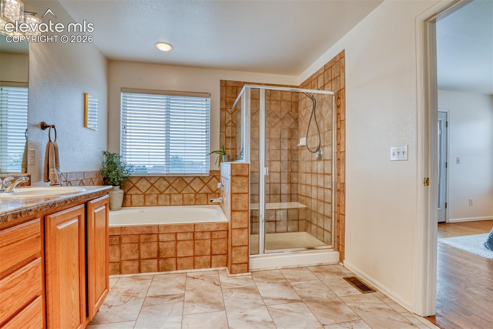 Dual vanity with integrated sinks, built-in bathtub, and a tiled shower with a glass enclosure