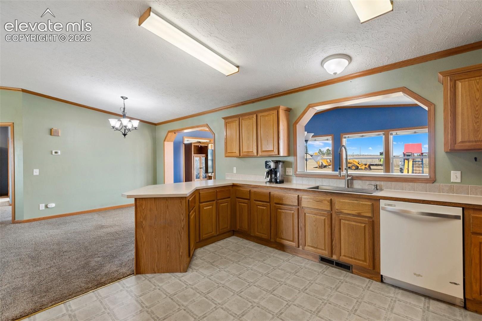 Kitchen with wood-finish cabinetry, a stainless steel sink, and a white dishwasher