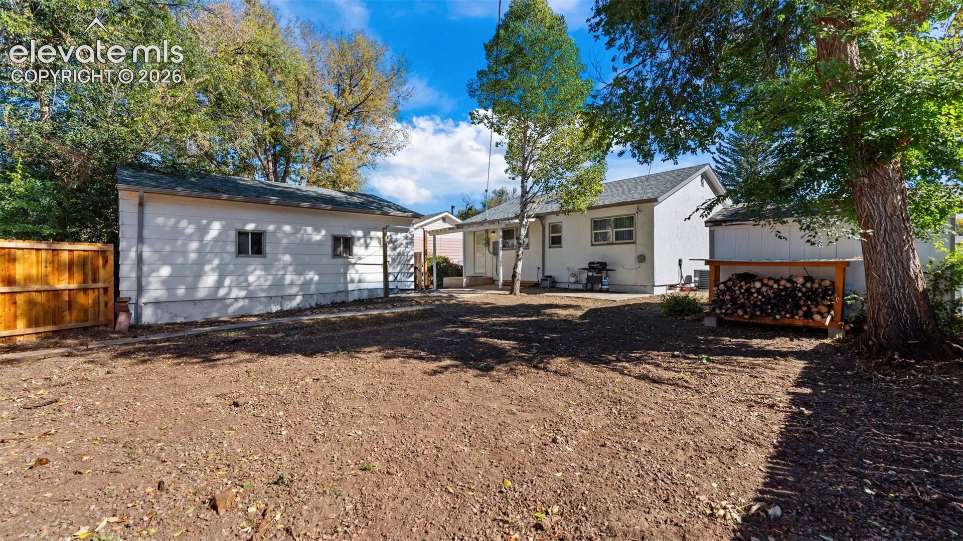 Backyard area featuring a detached garage, wooden perimeter fencing, and mature trees