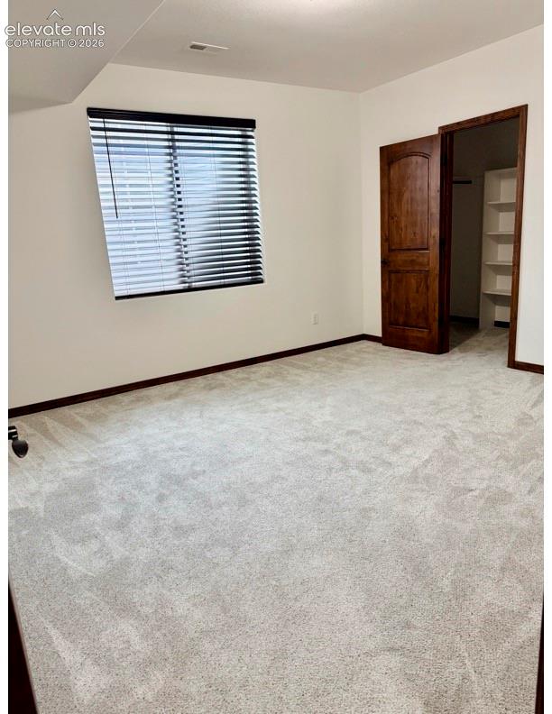Spacious room featuring light-colored carpeting, white wall paint, and dark wood trim