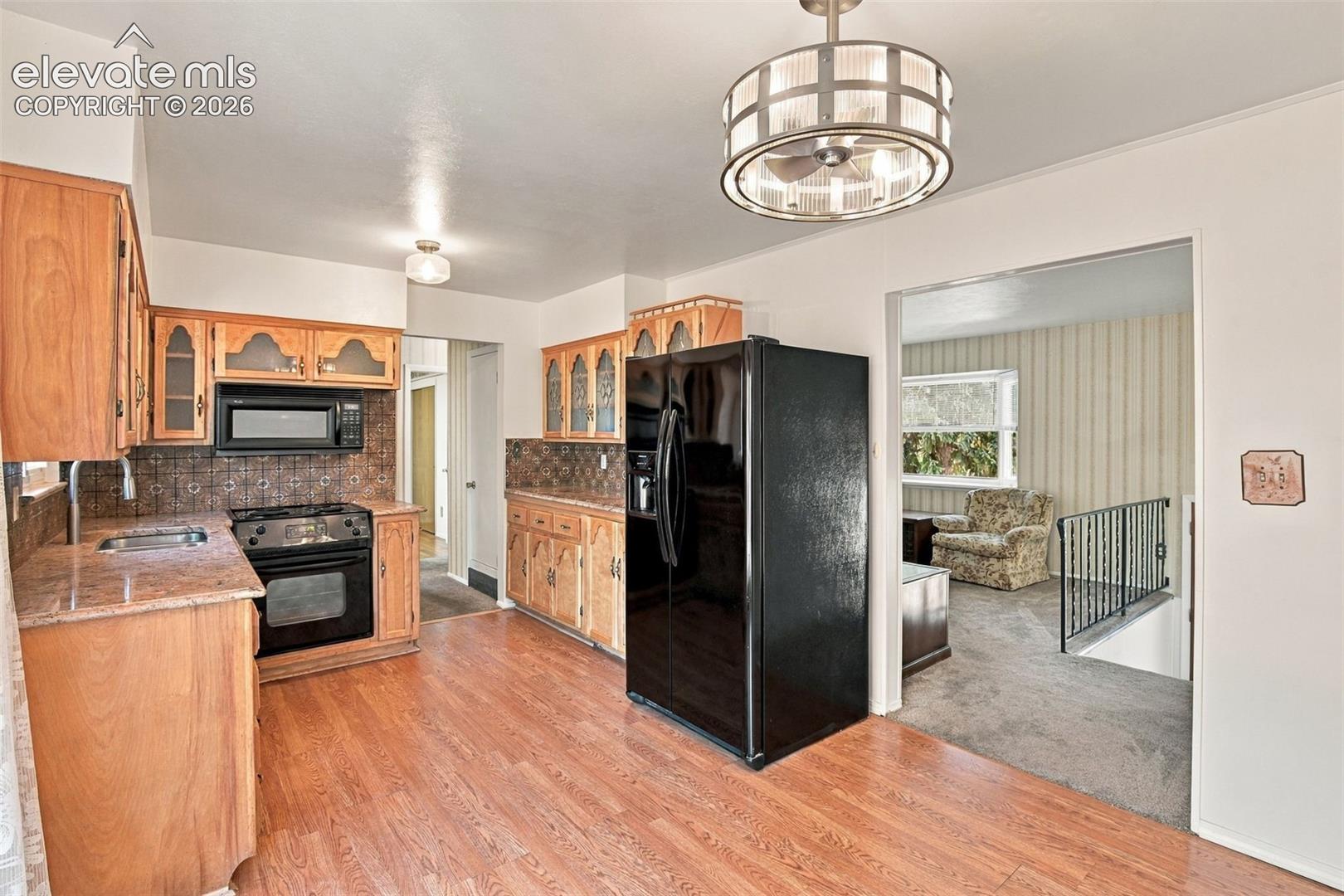 Kitchen featuring wood cabinetry, stone-finish countertops, tile backsplash, wood-finish flooring, and a circular drum-style ceiling light fixture