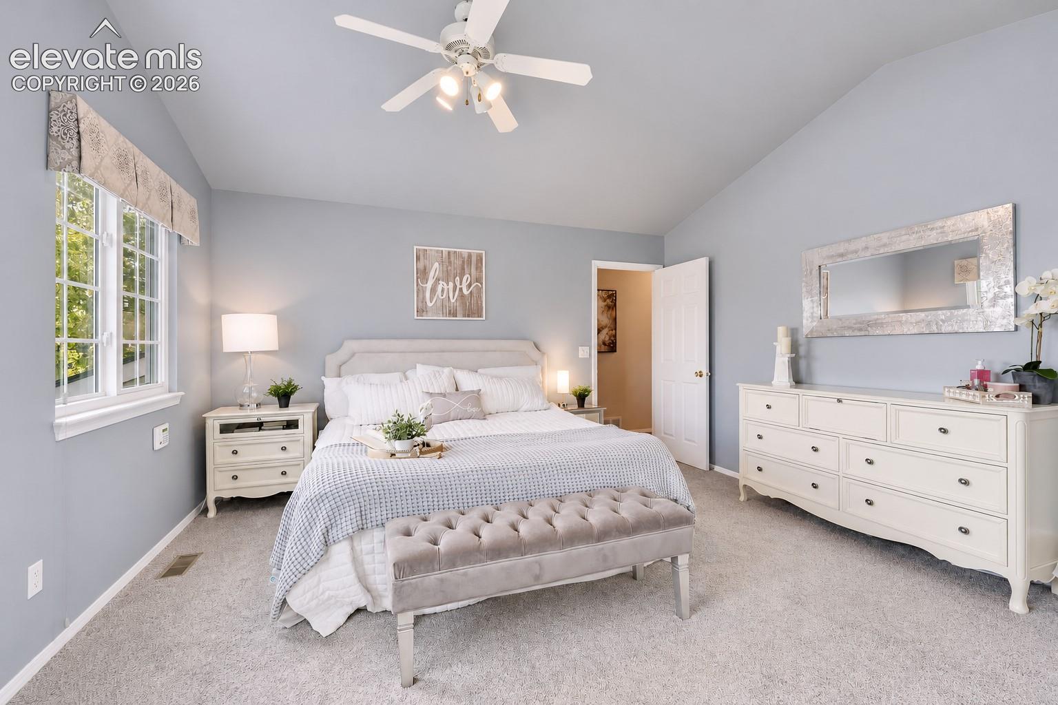 Vaulted upper level Primary Bedroom with a lighted ceiling fan, neutral carpet, and window that brings in lots of natural light.