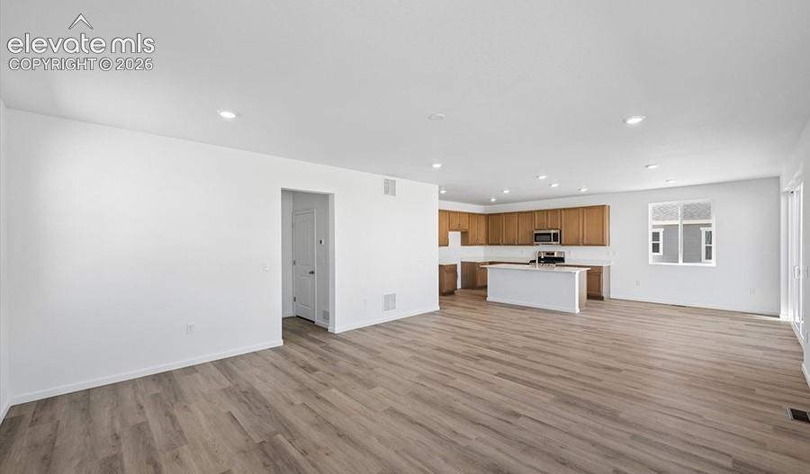 Open-concept interior featuring wood-finish flooring, recessed lighting, a center kitchen island, and wood-finish cabinetry