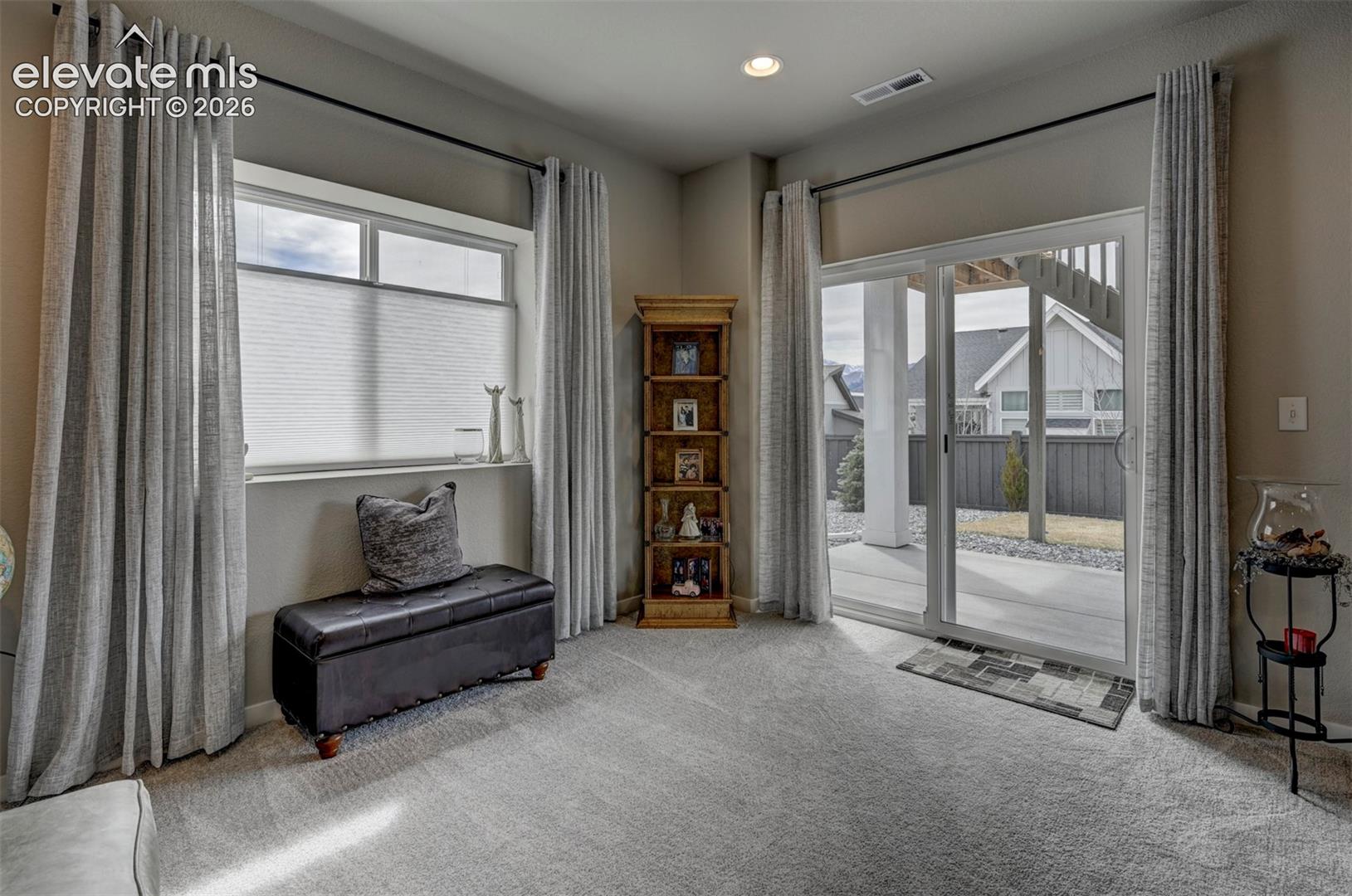 Carpeted flooring, recessed lighting, expansive sliding glass door, and large window with blinds