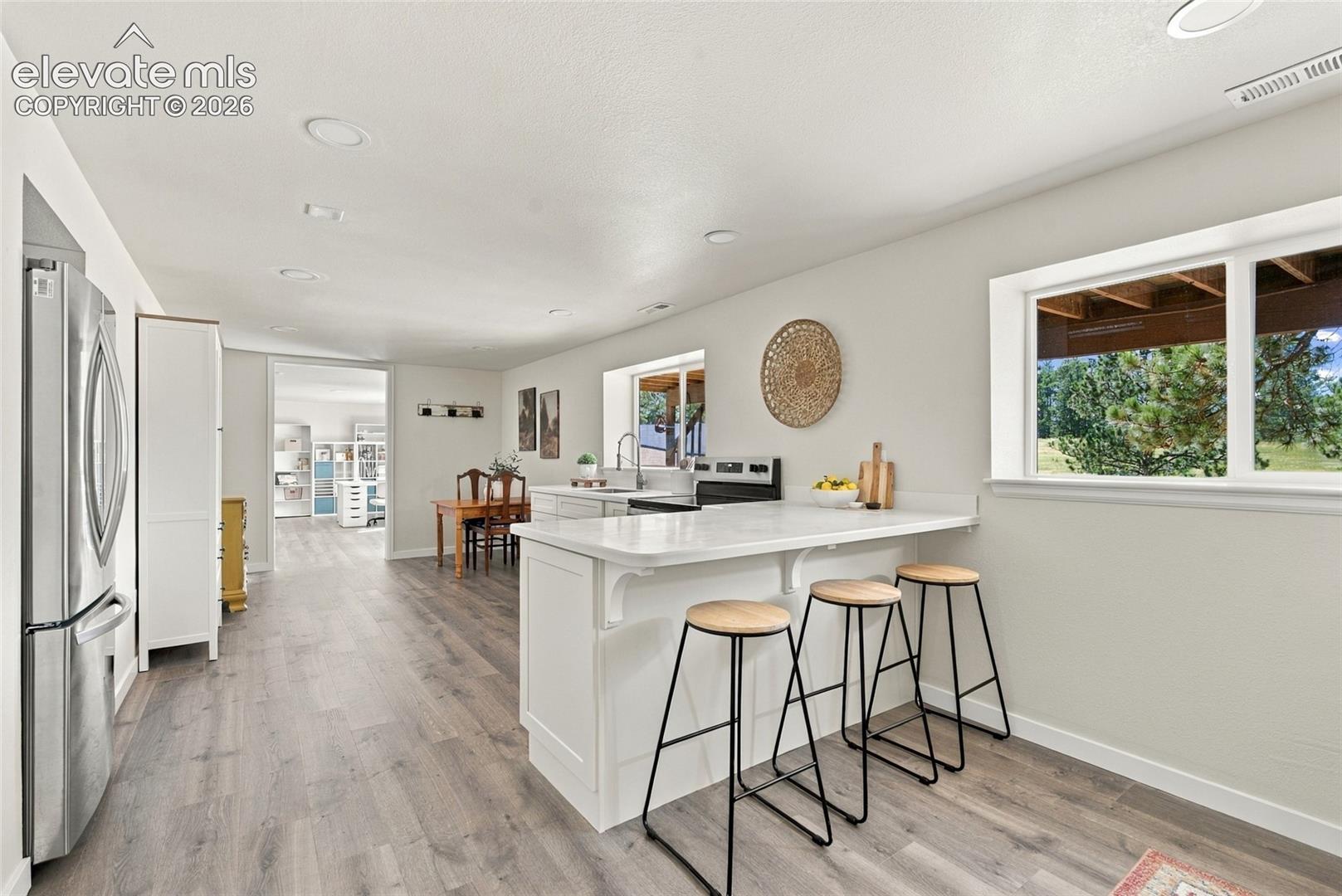 Basement Kitchen with white cabinetry, light countertops, stainless steel appliances, wood-finish flooring, and recessed lighting