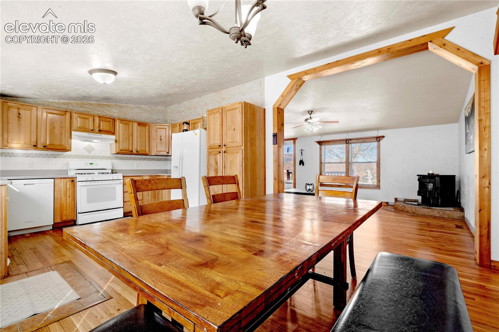 Unfurnished dining area with a textured ceiling, ceiling fan, light wood-type flooring, and vaulted ceiling