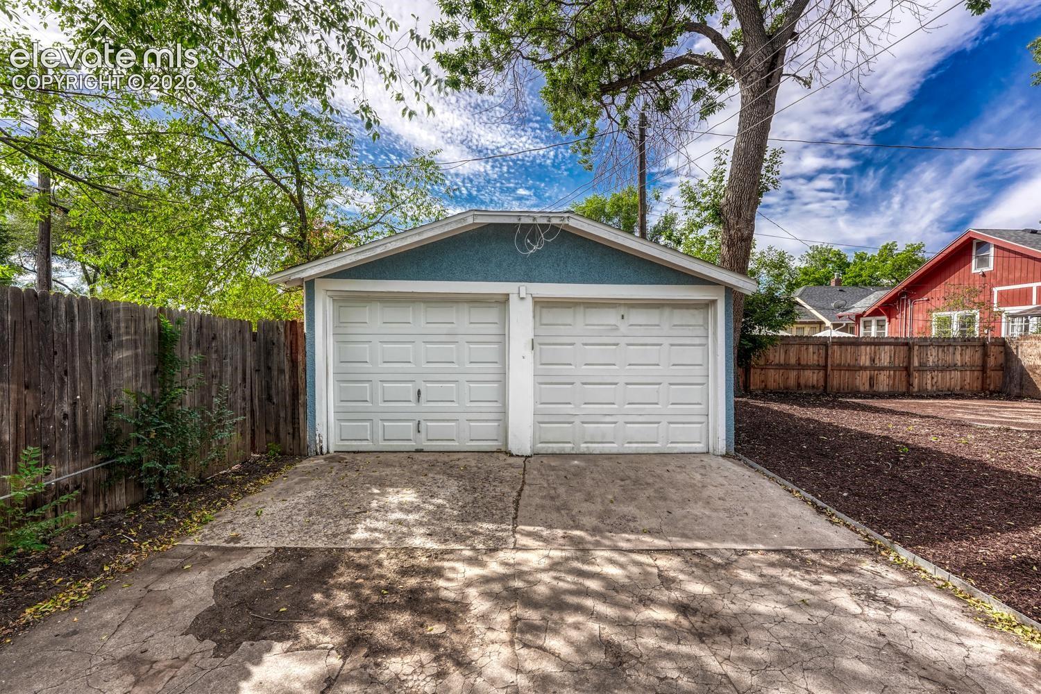 Detached two-car garage with white paneled doors and a blue exterior finish