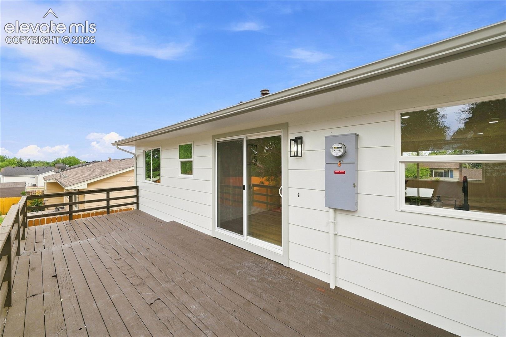 Expansive wood deck with dark railings, white siding, and exterior lighting