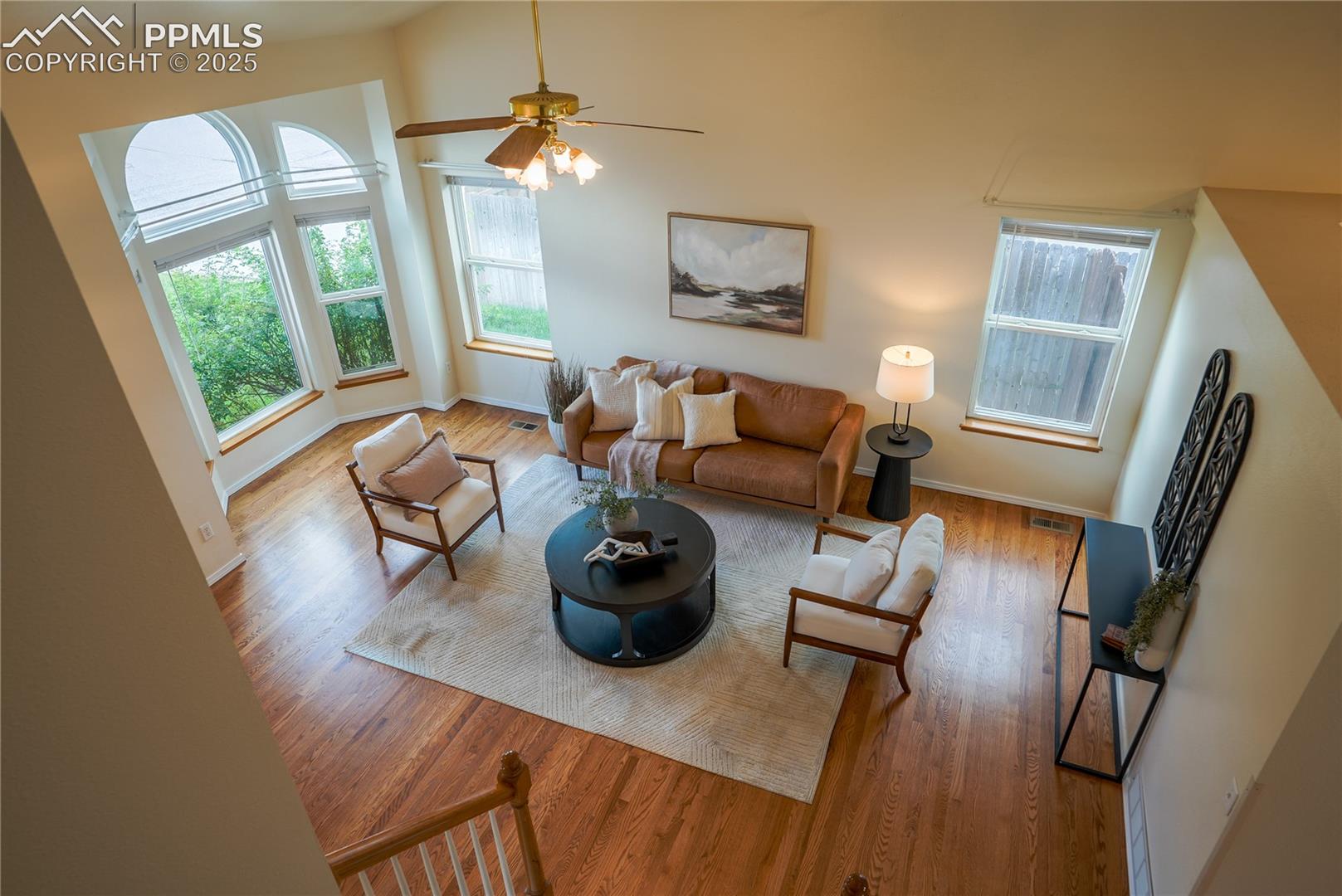 Living room with wood finished floors, healthy amount of natural light, and a ceiling fan