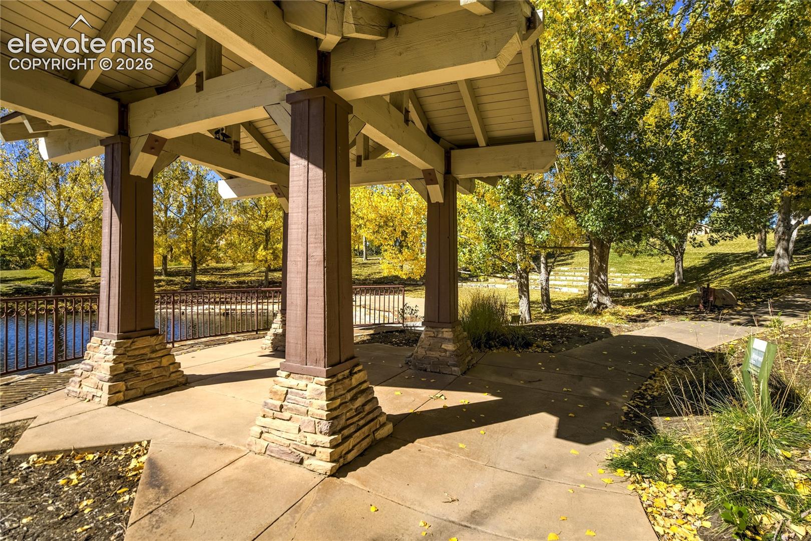 A beautifully crafted pavilion with substantial timber beams + stone accents offers a sheltered place to pause and enjoy the surrounding trees, water features + established natural setting.