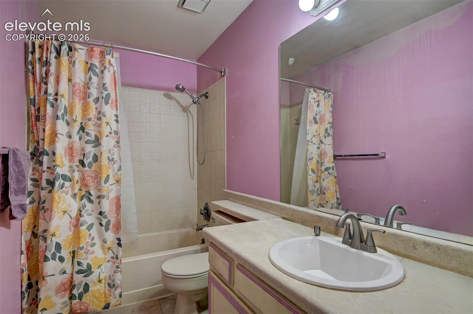 Bathroom featuring a built-in vanity with an oval sink and brushed nickel faucet, a large wall-mounted mirror, a tub/shower combination with white tiled surround, and overhead lighting