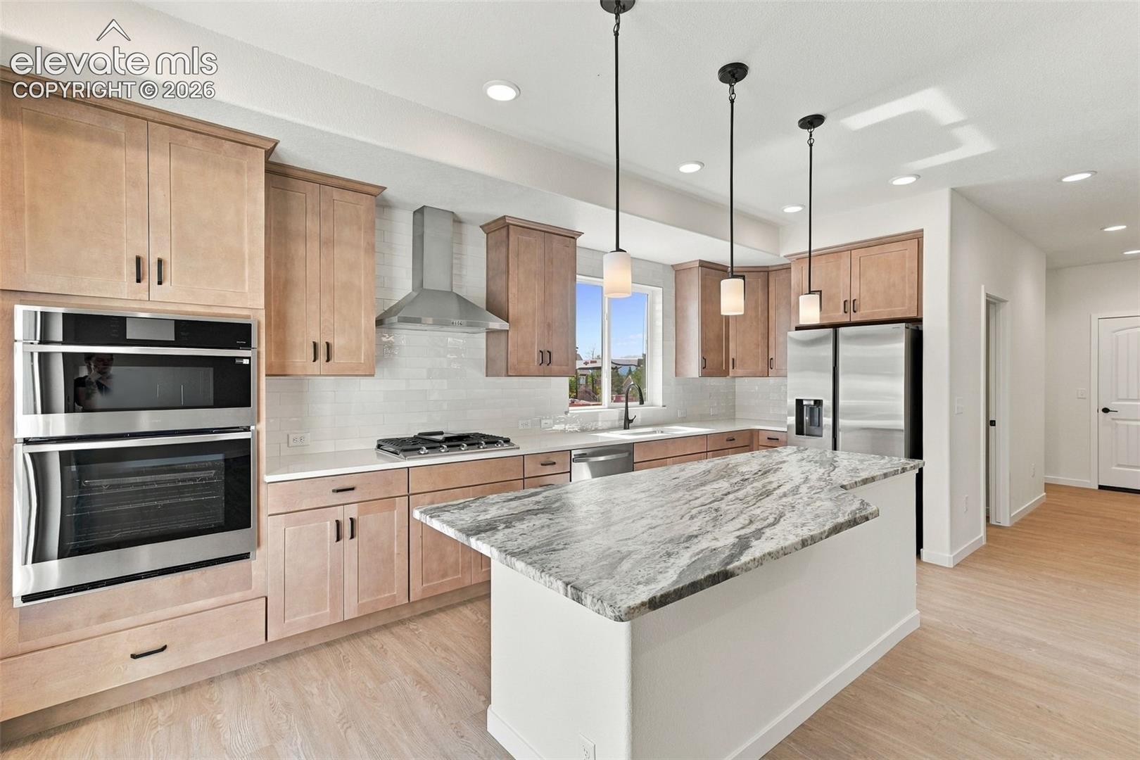 The Kitchen features stainless steel appliances, light maple cabinets with pecan stain, a large kitchen island with quartz countertop, and LVP flooring.