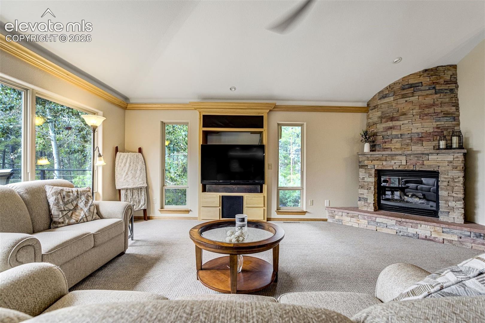 Stone-clad fireplace with a hearth, built-in entertainment center, and large windows