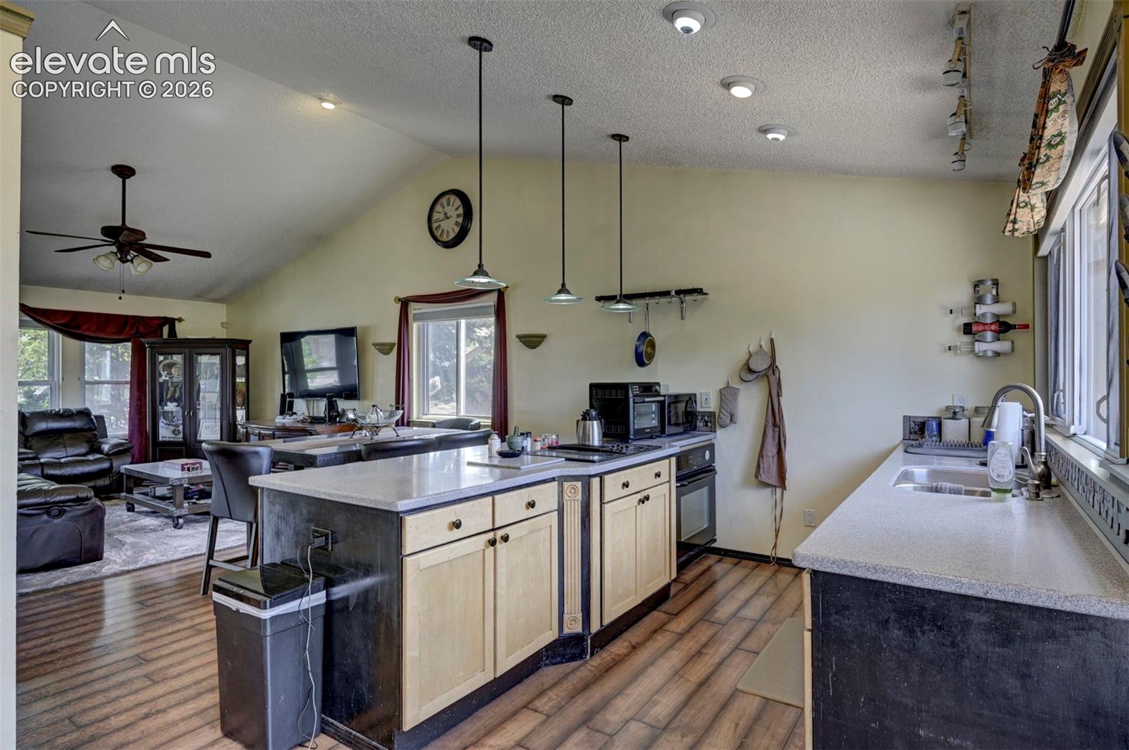 Open-concept kitchen featuring an island with light-toned cabinetry, light countertops, wood-finish flooring, and recessed ceiling lighting