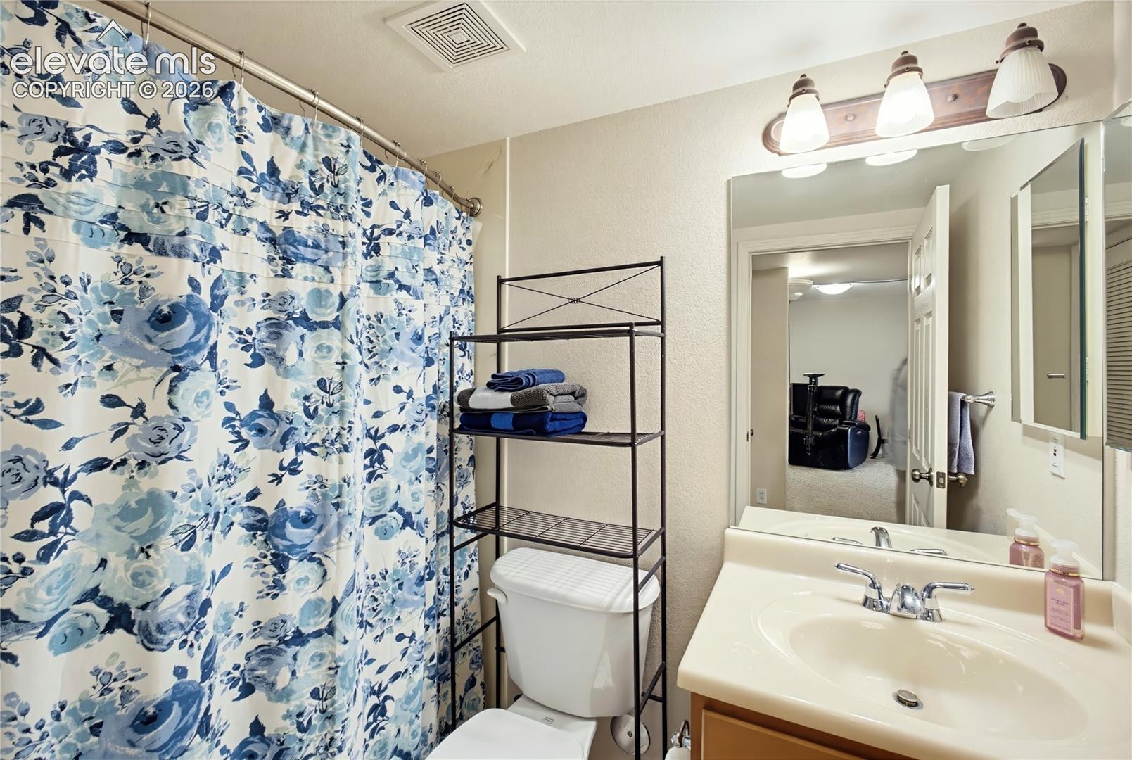 Vanity with integrated sink and chrome faucet, wall-mounted mirror, and three-light fixture