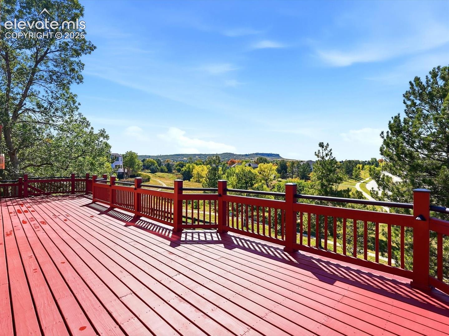 Expansive wooden deck featuring horizontal railings and mesa landscape surroundings
