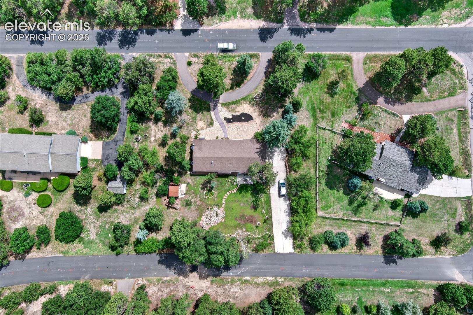 Expansive property featuring mature trees, paved driveways, a shingled roof 