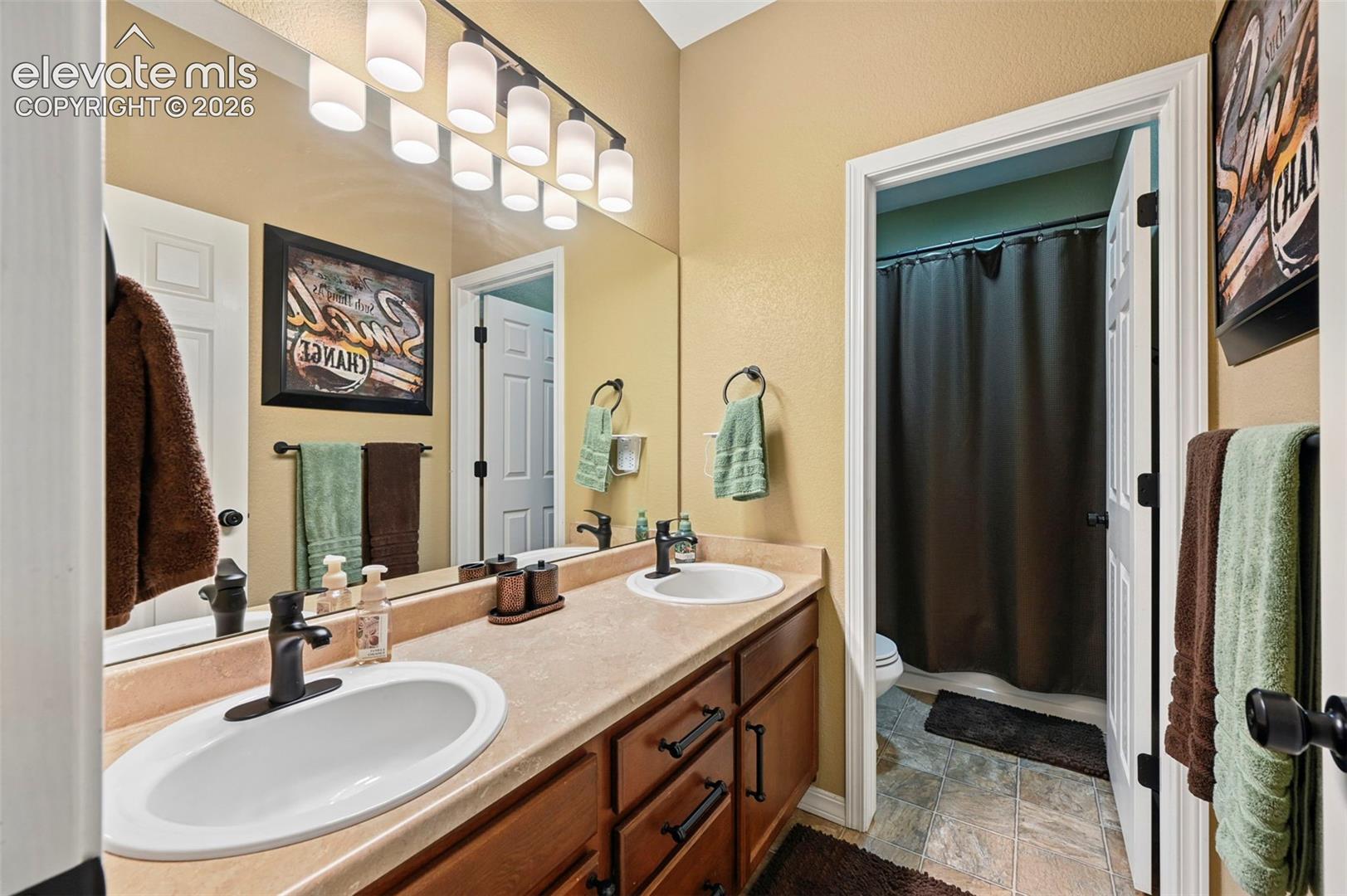 Dual vanity with undermount sinks, wood-finish cabinetry, and matte black fixtures