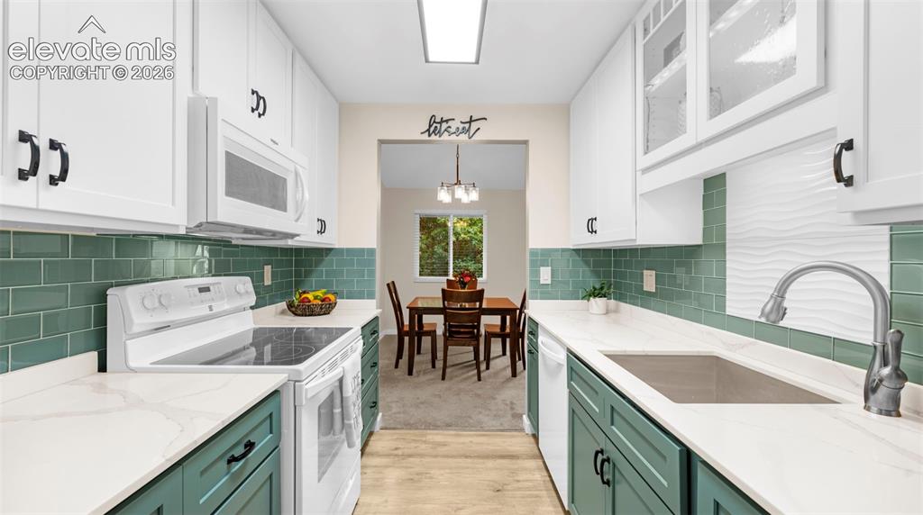 Galley kitchen featuring white upper cabinetry, teal lower cabinetry, and white countertops